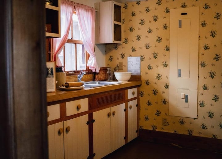 Example photo: Vintage kitchen with floral wallpaper, cream cabinets and pink curtains