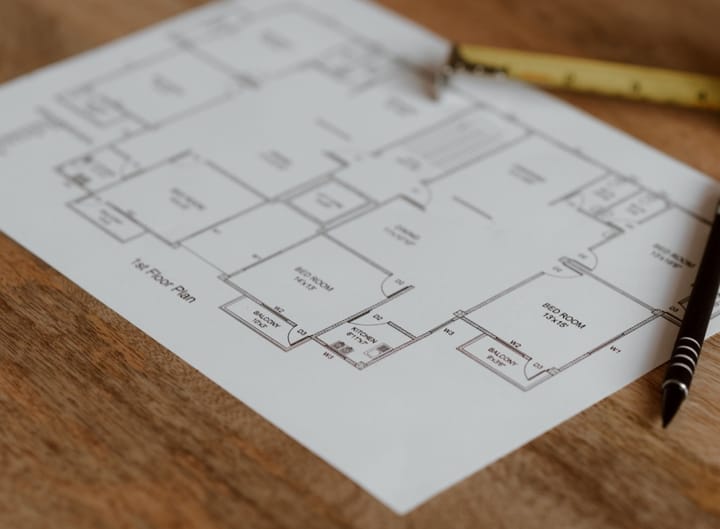 Example photo: Printed apartment floor plan on a wooden desk beside a pen