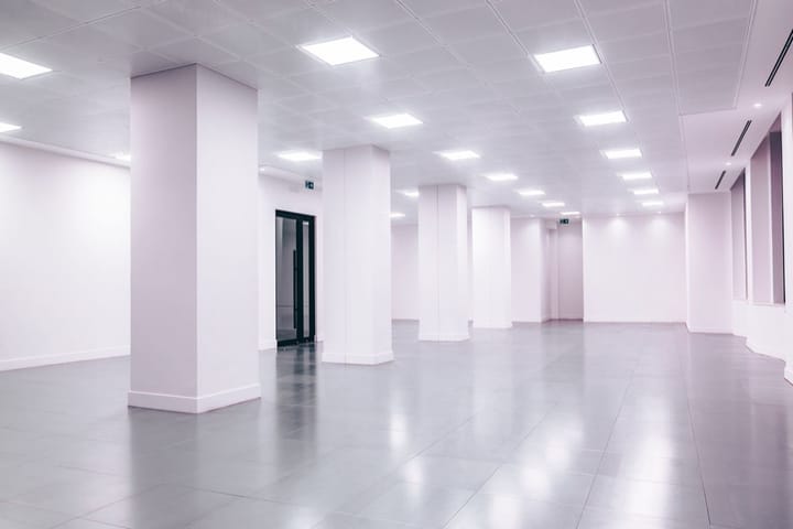 Example photo: Empty white commercial space with square columns and ceiling lights