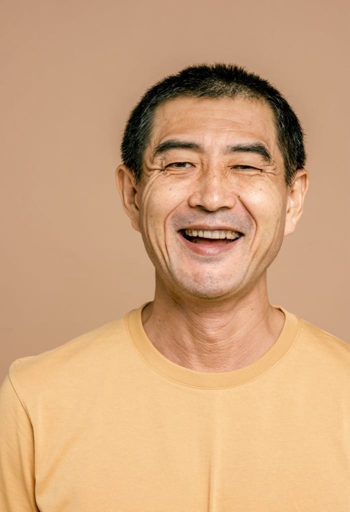 Example photo: Cheerful older man in a T-shirt facing the camera on a plain background