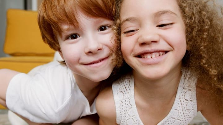 Example photo: Two smiling kids cheek to cheek, a red-haired boy and a curly-haired girl
