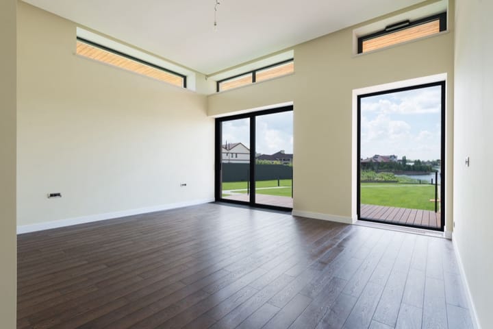 Example photo: Empty room with dark wood floors, high windows and glass doors onto a lawn