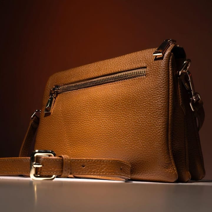 Example photo: Tan leather crossbody bag on a warm orange-brown backdrop